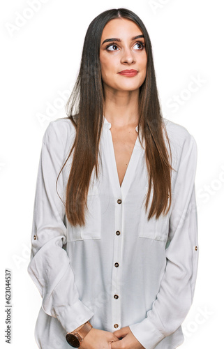 Young beautiful woman wearing casual white shirt smiling looking to the side and staring away thinking.