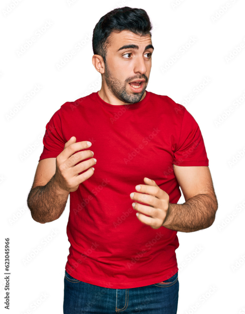 Hispanic man with beard wearing casual red t shirt surprised with hand on head for mistake, remember error. forgot, bad memory concept. Hispanic man with beard wearing casual red t shirt surprised with hand on head for mistake, remember error. forgot, bad memory concept.