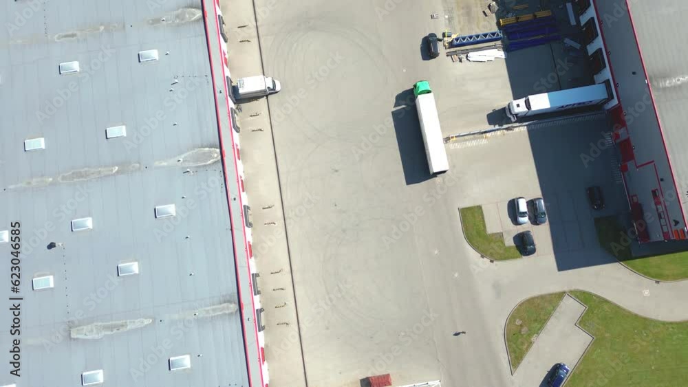 Aerial view of goods warehouse. Logistics center in industrial city zone from above. Aerial view of trucks loading at logistic center. View from drone. Aerial view of goods warehouse. Logistics center in industrial city zone from above. Aerial view of trucks loading at logistic center. View from drone.