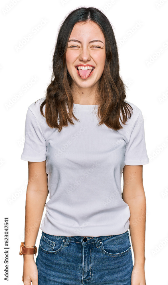Young beautiful woman wearing casual white t shirt sticking tongue out happy with funny expression. emotion concept. Young beautiful woman wearing casual white t shirt sticking tongue out happy with funny expression. emotion concept.