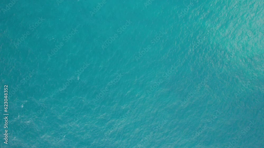 Top view of the turquoise sea with waves and the beach. Waves lifting sand from the bottom create an unusual pattern. White foam. The gradient is blue. Video for background. Thailand, Phuket Top view of the turquoise sea with waves and the beach. Waves lifting sand from the bottom create an unusual pattern. White foam. The gradient is blue. Video for background. Thailand, Phuket