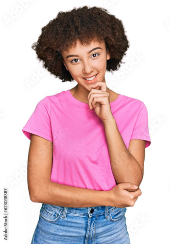 Young hispanic girl wearing casual clothes looking confident at the camera with smile with crossed arms and hand raised on chin. thinking positive.