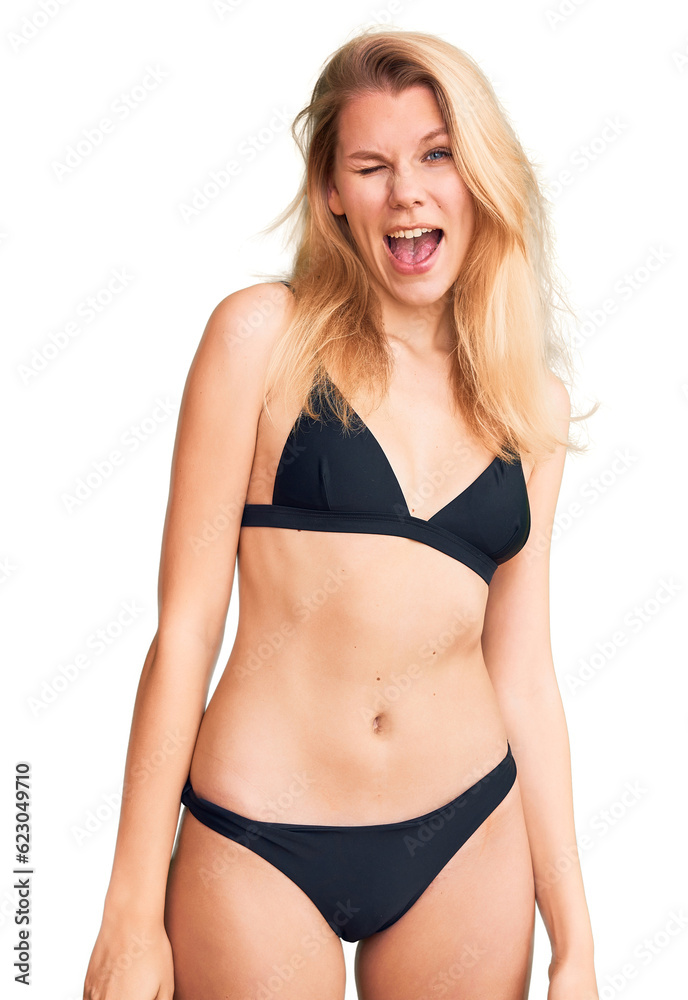 Obraz premium Young beautiful blonde woman wearing bikini winking looking at the camera with sexy expression, cheerful and happy face.