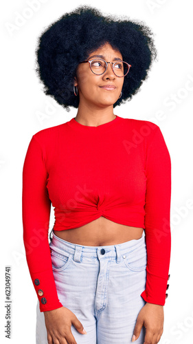 Young african american girl wearing casual clothes and glasses smiling looking to the side and staring away thinking.