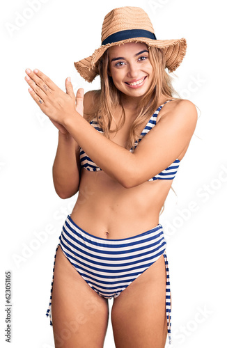 Young beautiful blonde woman wearing bikini and hat clapping and applauding happy and joyful, smiling proud hands together