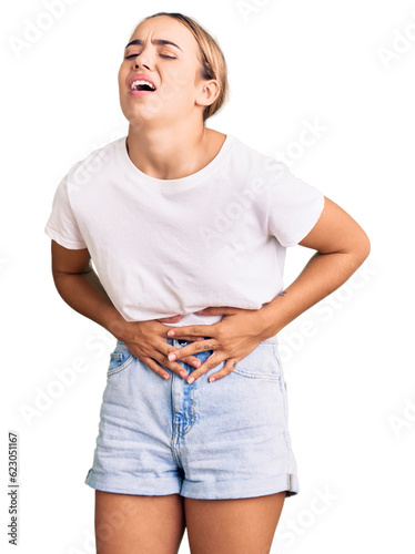 Young beautiful blonde woman wearing casual white tshirt with hand on stomach because nausea, painful disease feeling unwell. ache concept. photo