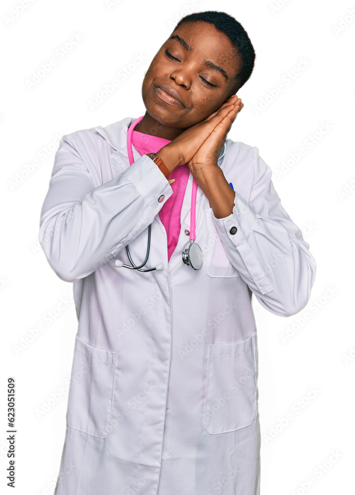 Young african american woman wearing doctor uniform and stethoscope sleeping tired dreaming and posing with hands together while smiling with closed eyes. Young african american woman wearing doctor uniform and stethoscope sleeping tired dreaming and posing with hands together while smiling with closed eyes.