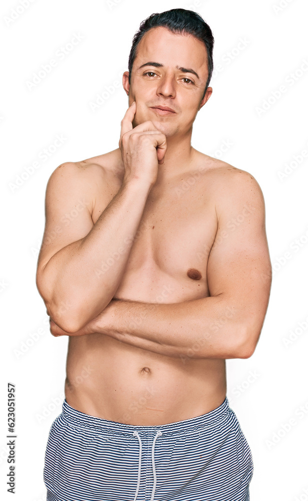 Fototapeta premium Handsome young man wearing swimwear shirtless with hand on chin thinking about question, pensive expression. smiling and thoughtful face. doubt concept.