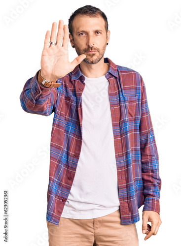 Young handsome man wearing casual clothes doing stop sing with palm of the hand. warning expression with negative and serious gesture on the face.