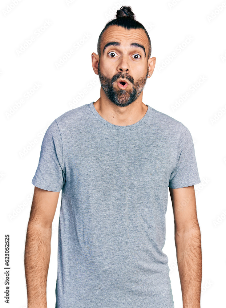 Hispanic man with ponytail wearing casual grey t shirt afraid and shocked with surprise expression, fear and excited face. Hispanic man with ponytail wearing casual grey t shirt afraid and shocked with surprise expression, fear and excited face.
