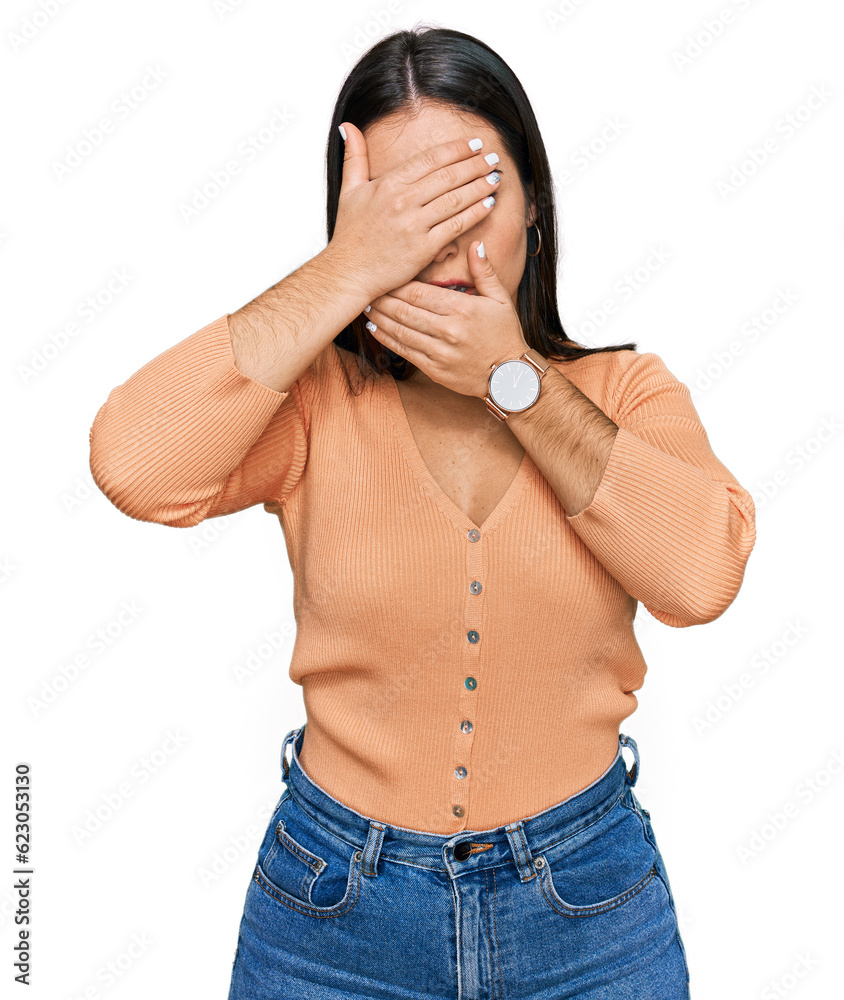 Young hispanic woman wearing casual clothes covering eyes and mouth with hands, surprised and shocked. hiding emotion Young hispanic woman wearing casual clothes covering eyes and mouth with hands, surprised and shocked. hiding emotion