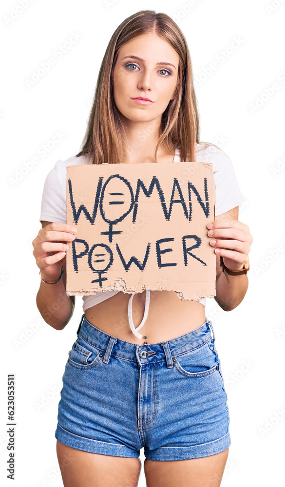 Young beautiful blonde woman holding woman power banner thinking attitude and sober expression looking self confident Young beautiful blonde woman holding woman power banner thinking attitude and sober expression looking self confident