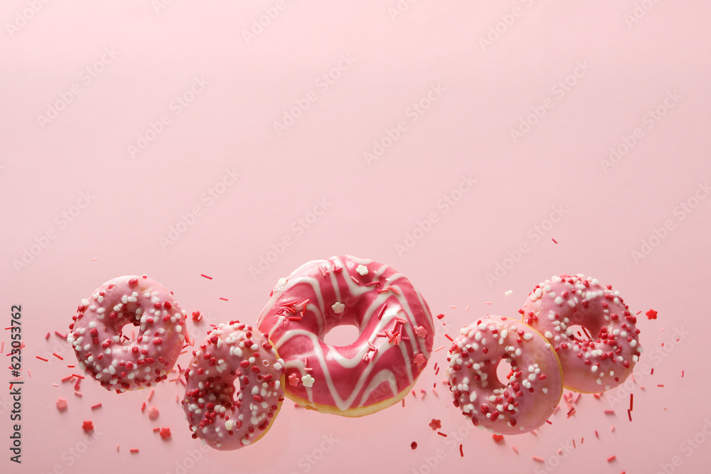 Pink donuts levitate in the air on a pink background