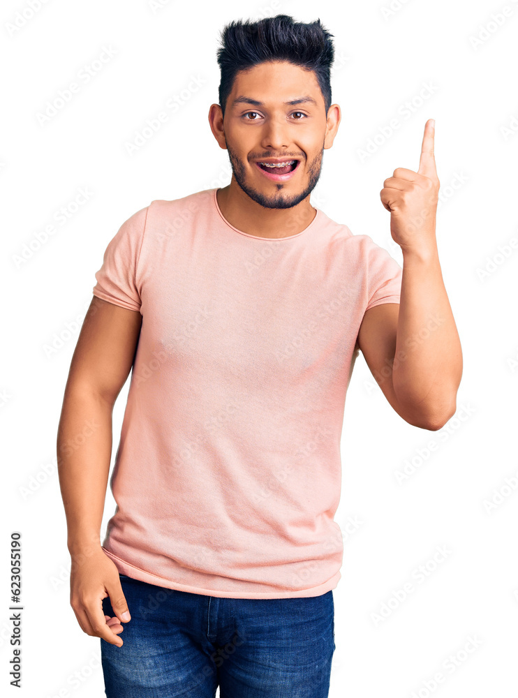 Handsome latin american young man wearing casual clothes pointing finger up with successful idea. exited and happy. number one. Handsome latin american young man wearing casual clothes pointing finger up with successful idea. exited and happy. number one.