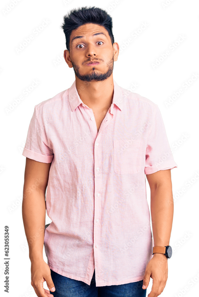 Handsome latin american young man wearing casual summer shirt puffing cheeks with funny face. mouth inflated with air, crazy expression.
