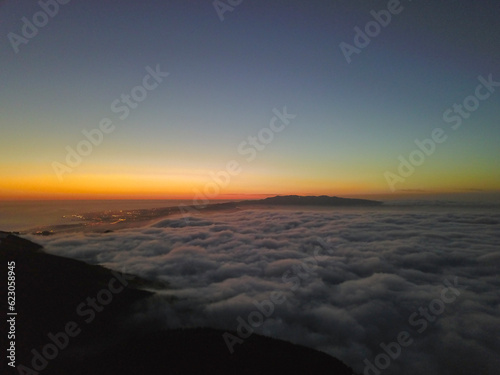 Sunset in the mountains above the clouds with the city lights of Ribeira Grande in the background. São Miguel Island in the Azores.