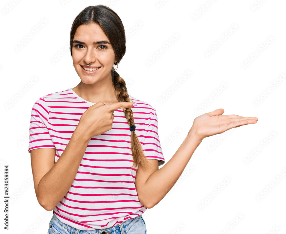 Young hispanic woman wearing casual clothes amazed and smiling to the camera while presenting with hand and pointing with finger. Young hispanic woman wearing casual clothes amazed and smiling to the camera while presenting with hand and pointing with finger.