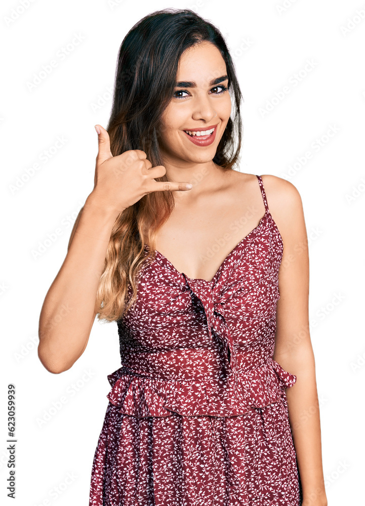 Beautiful hispanic woman wearing summer dress smiling doing phone gesture with hand and fingers like talking on the telephone. communicating concepts. Beautiful hispanic woman wearing summer dress smiling doing phone gesture with hand and fingers like talking on the telephone. communicating concepts.