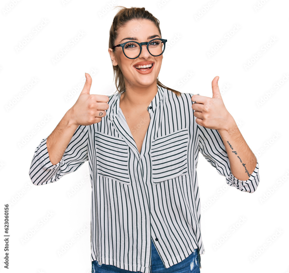 Young caucasian woman wearing business shirt and glasses success sign doing positive gesture with hand, thumbs up smiling and happy. cheerful expression and winner gesture. Young caucasian woman wearing business shirt and glasses success sign doing positive gesture with hand, thumbs up smiling and happy. cheerful expression and winner gesture.