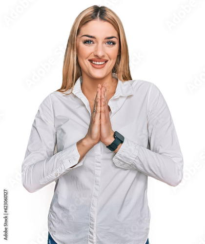 Young caucasian woman wearing casual clothes praying with hands together asking for forgiveness smiling confident.