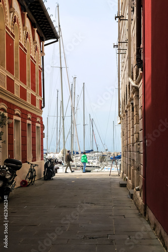 View from a narrow street of an old European city to boats and yachts in the port. Piran  Slovenia.