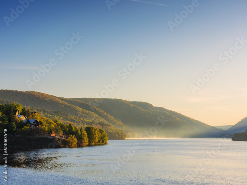 mountainous autumn landscape with lake. nature background with trees on the shore in fall colors. warm sunny weather. romania, cluj region