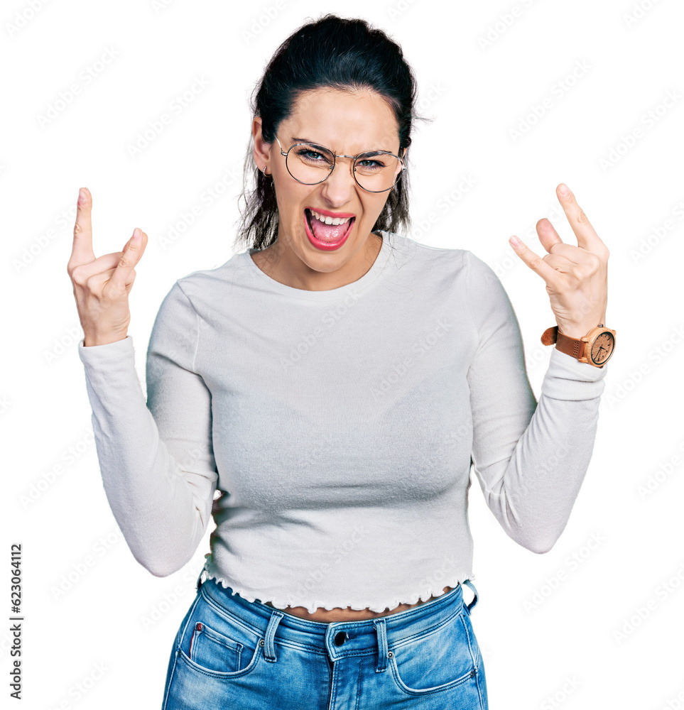 Young hispanic woman wearing casual clothes shouting with crazy expression doing rock symbol with hands up. music star. heavy concept. Young hispanic woman wearing casual clothes shouting with crazy expression doing rock symbol with hands up. music star. heavy concept.