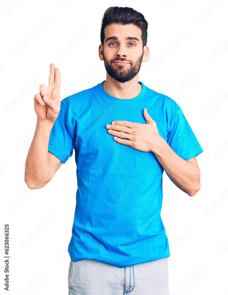 Young handsome man with beard wearing casual t-shirt smiling swearing with hand on chest and fingers up, making a loyalty promise oath