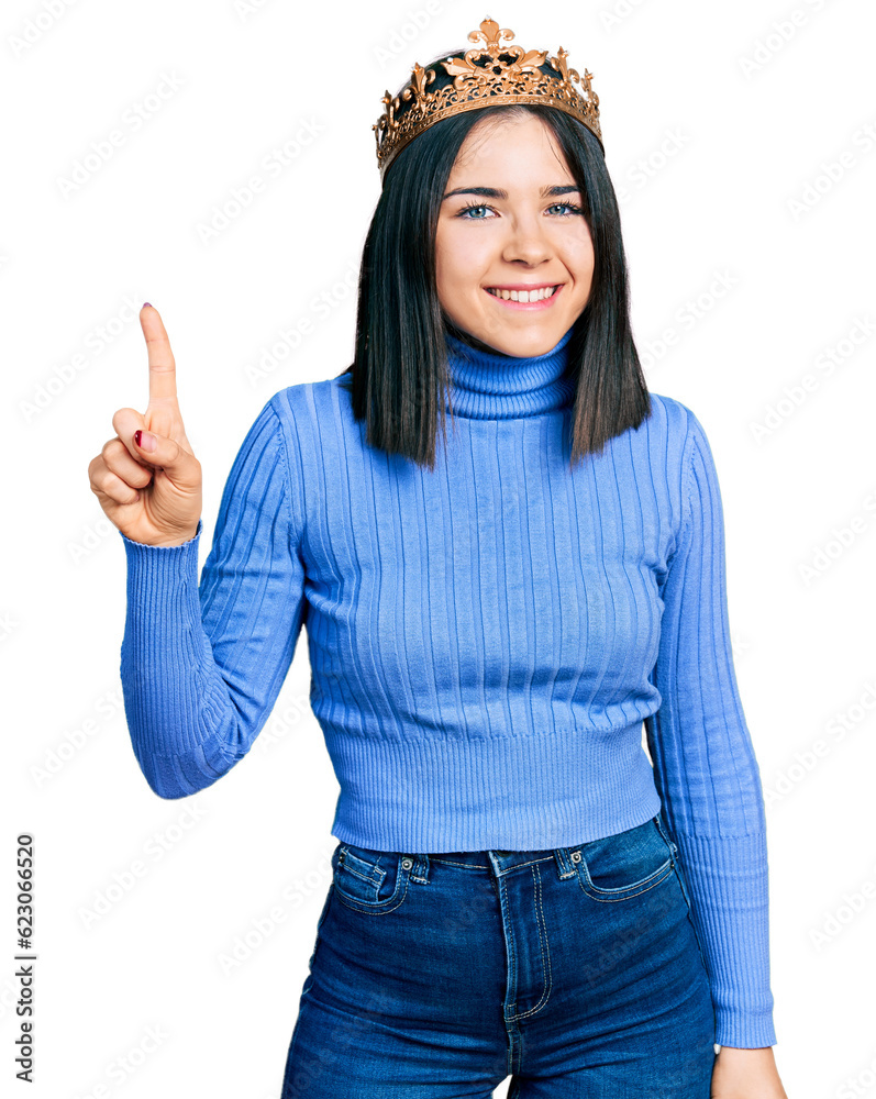 Φωτογραφία Young brunette woman with blue eyes wearing princess crown showing and pointing up with finger number one while smiling confident and happy