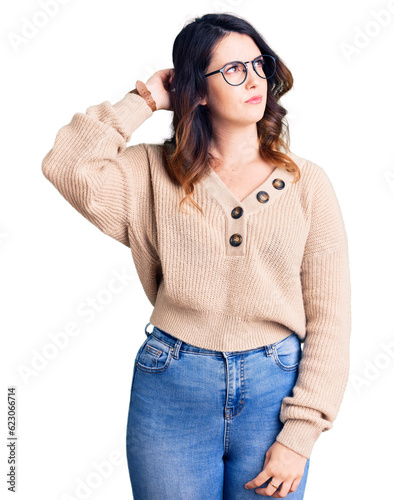 Beautiful young brunette woman wearing casual clothes and glasses confuse and wondering about question. uncertain with doubt, thinking with hand on head. pensive concept.