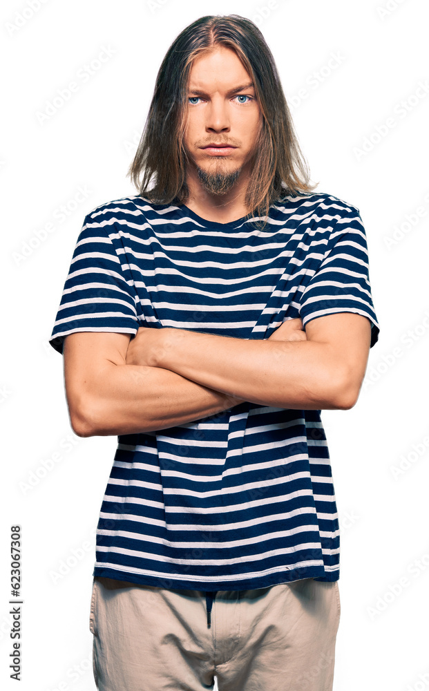 Handsome caucasian man with long hair wearing casual striped t-shirt skeptic and nervous, disapproving expression on face with crossed arms. negative person. Handsome caucasian man with long hair wearing casual striped t-shirt skeptic and nervous, disapproving expression on face with crossed arms. negative person.
