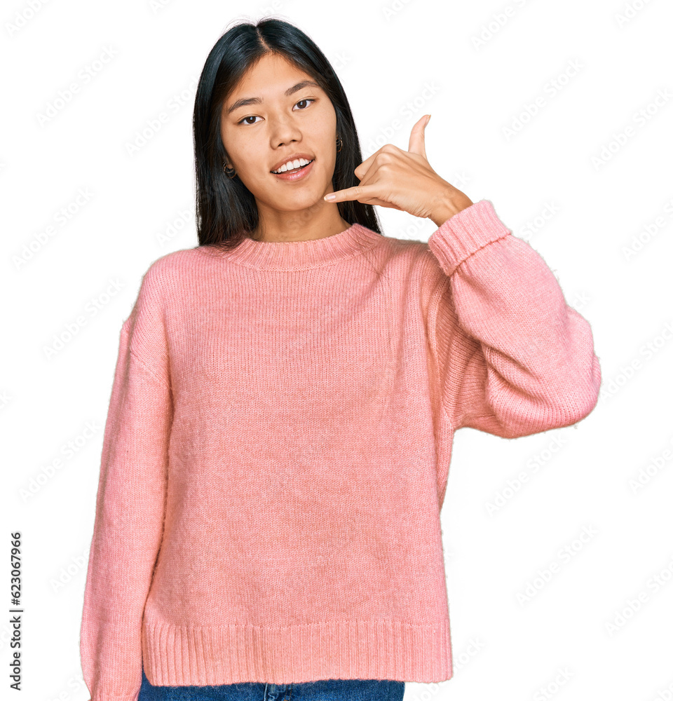 Beautiful young asian woman wearing casual winter sweater smiling doing phone gesture with hand and fingers like talking on the telephone. communicating concepts. Beautiful young asian woman wearing casual winter sweater smiling doing phone gesture with hand and fingers like talking on the telephone. communicating concepts.