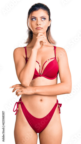 Young beautiful woman wearing bikini with hand on chin thinking about question, pensive expression. smiling with thoughtful face. doubt concept. © Krakenimages.com