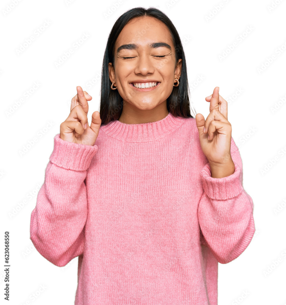 Young asian woman wearing casual winter sweater gesturing finger crossed smiling with hope and eyes closed. luck and superstitious concept. Young asian woman wearing casual winter sweater gesturing finger crossed smiling with hope and eyes closed. luck and superstitious concept.