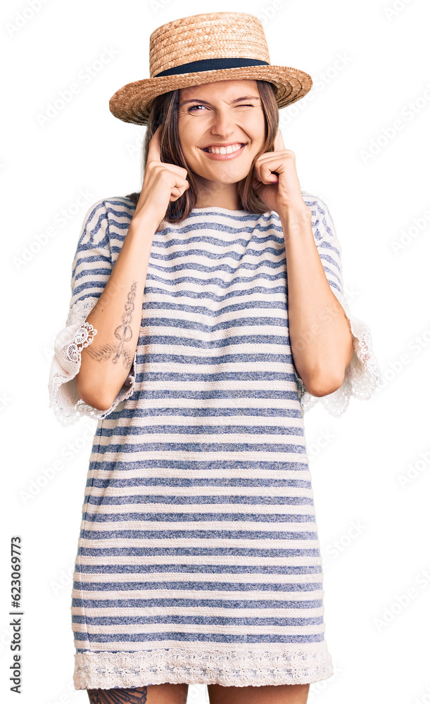 Beautiful caucasian woman wearing summer hat covering ears with fingers with annoyed expression for the noise of loud music. deaf concept. Beautiful caucasian woman wearing summer hat covering ears with fingers with annoyed expression for the noise of loud music. deaf concept.