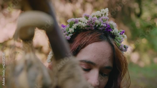 young girl holding her druidic staff wearing a crown of flowers close shot photo