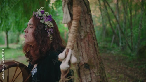 druid girl in a forest playing a shamanic drum side view close shot photo