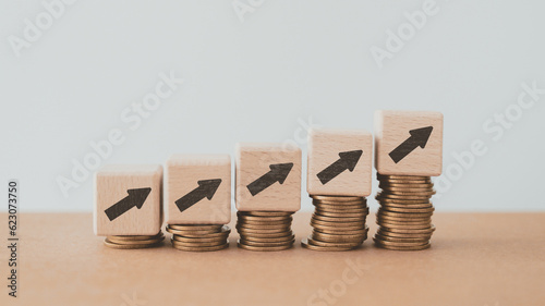 For financial growth, interest rate increase, inflation, high price and tax rise concept. Arrow up sign on wooden cube blocks above stack of coins including copy space #623073750