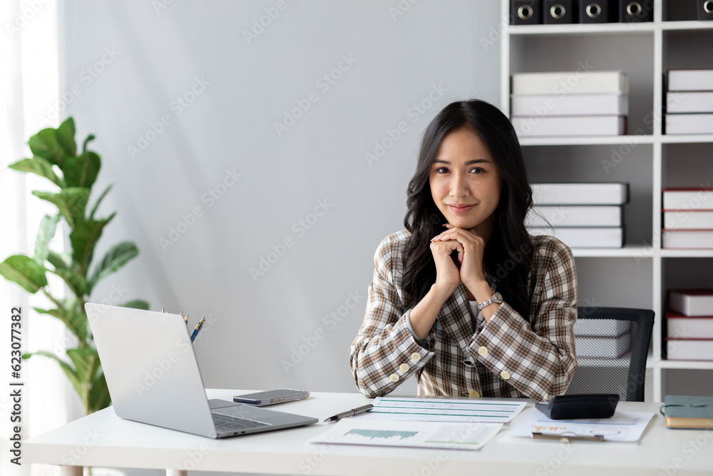 A beautiful Asian businesswoman sitting in her private office, she is checking company financial documents, she is a female executive of a startup company. Concept of financial management. A beautiful Asian businesswoman sitting in her private office, she is checking company financial documents, she is a female executive of a startup company. Concept of financial management.