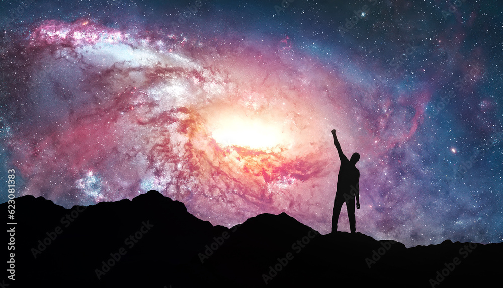 Fototapeta premium Silhouette of man standing on peak of mountaing with stars and galaxy in the night sky. Nightly starry space landscape. Success and motivation. Lifestyle and freedom concept.