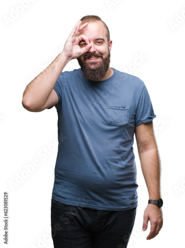 Young caucasian hipster man over isolated background doing ok gesture with hand smiling, eye looking through fingers with happy face.