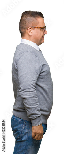 Middle age bussines arab man wearing glasses over isolated background looking to side, relax profile pose with natural face with confident smile.