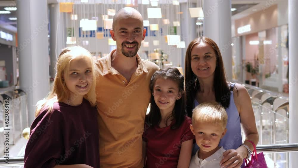 Portrait of a large happy family with three children in a shopping mall with bright shopping bags, they stand against the background of a bright store. Portrait of a large happy family with three children in a shopping mall with bright shopping bags, they stand against the background of a bright store.