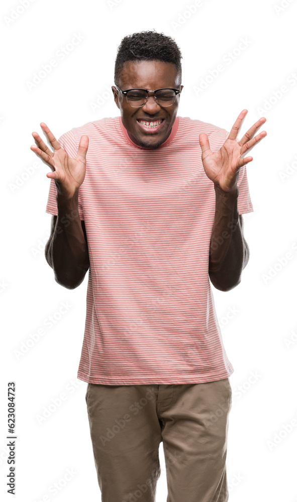 Young african american man wearing pink t-shirt celebrating mad and crazy for success with arms raised and closed eyes screaming excited. Winner concept Young african american man wearing pink t-shirt celebrating mad and crazy for success with arms raised and closed eyes screaming excited. Winner concept