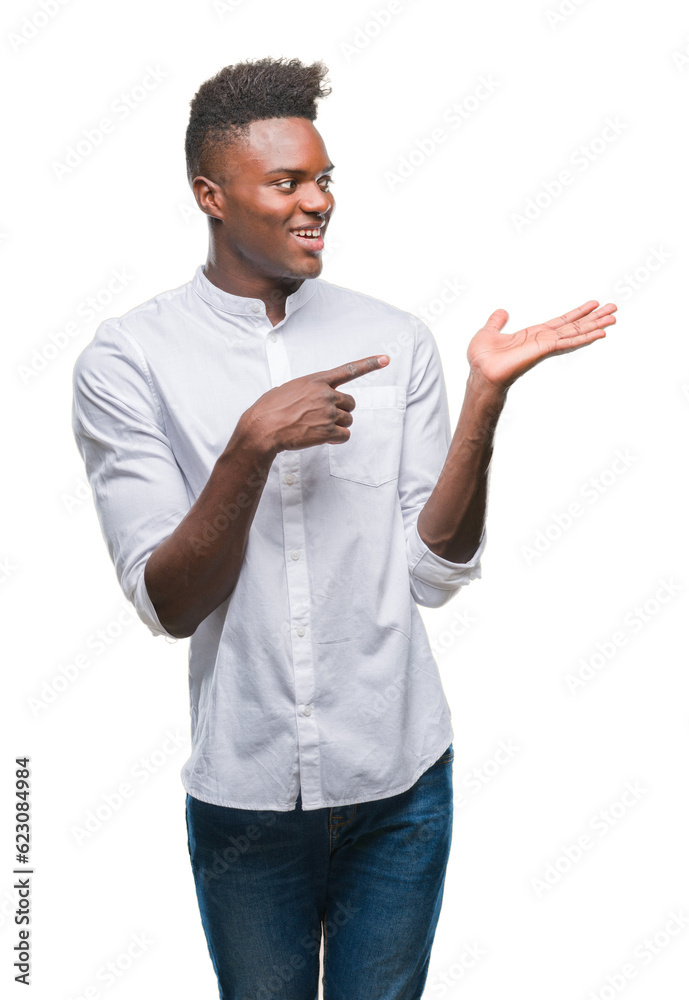 Young african american man over isolated background amazed and smiling to the camera while presenting with hand and pointing with finger. Young african american man over isolated background amazed and smiling to the camera while presenting with hand and pointing with finger.