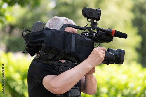 Side view of cameraman carrying camera on his shoulder