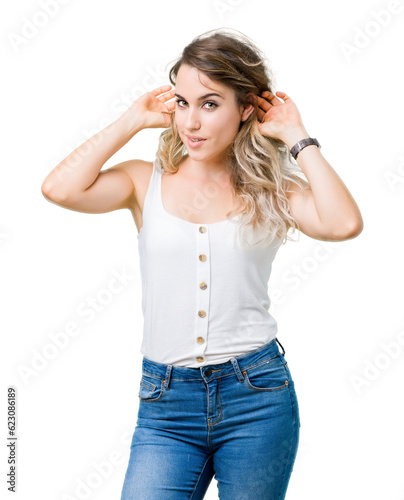 Beautiful young blonde woman over isolated background Smiling pulling ears with fingers, funny gesture. Audition problem