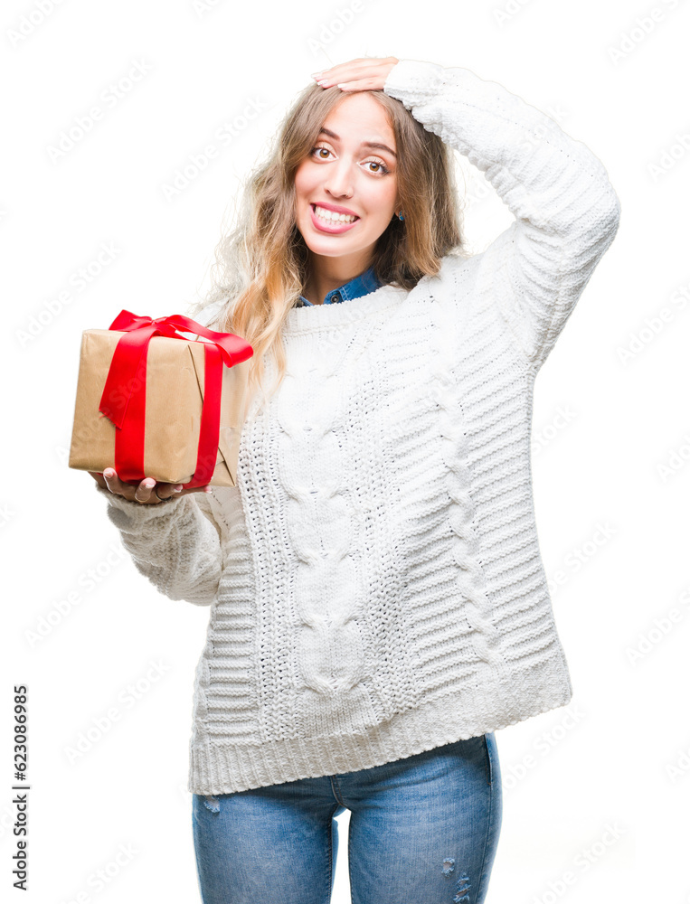 Beautiful young blonde woman holding gift over isolated background stressed with hand on head, shocked with shame and surprise face, angry and frustrated. Fear and upset for mistake. Beautiful young blonde woman holding gift over isolated background stressed with hand on head, shocked with shame and surprise face, angry and frustrated. Fear and upset for mistake.