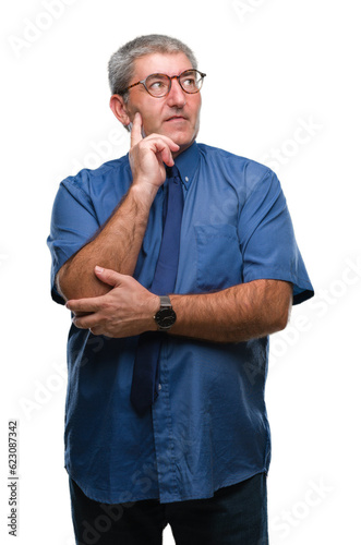 Handsome senior business man over isolated background with hand on chin thinking about question, pensive expression. Smiling with thoughtful face. Doubt concept. © Krakenimages.com