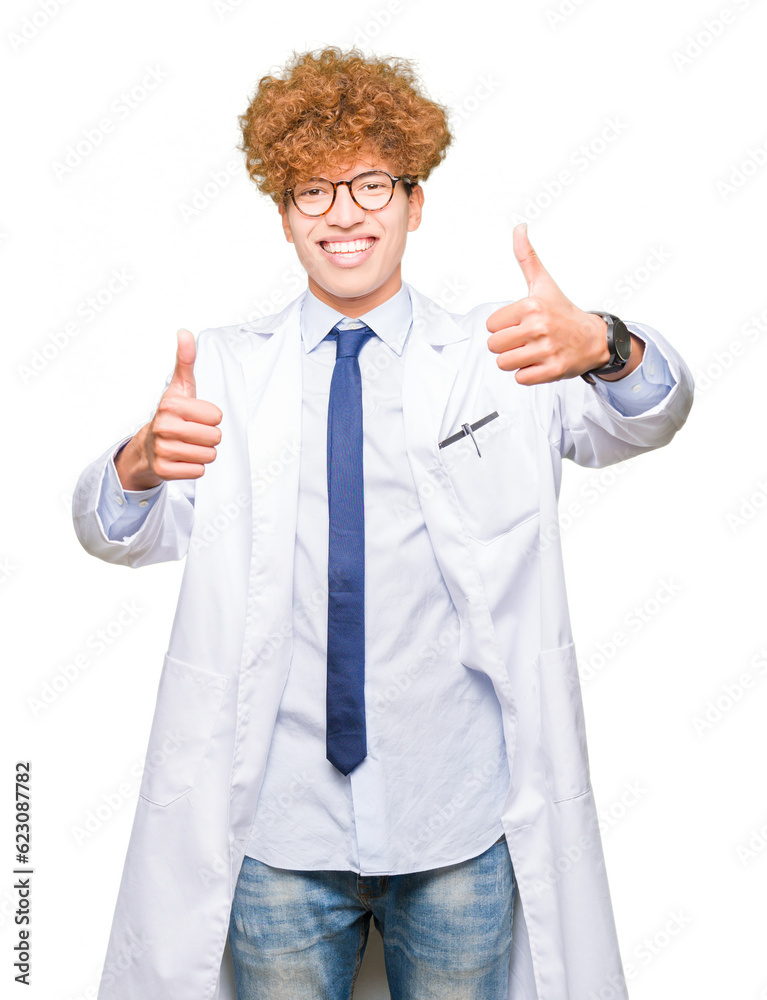 Young handsome scientist man wearing glasses approving doing positive gesture with hand, thumbs up smiling and happy for success. Looking at the camera, winner gesture.